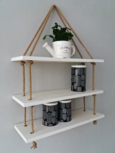 two white shelves with rope hanging from the top and one shelf holding coffee mugs