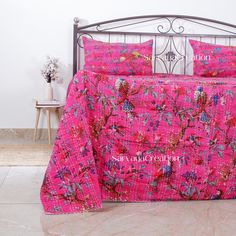 a bed with pink bedspread and matching pillowcases in a white room