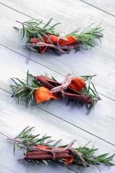 three dried carrots are sitting on a white wooden surface with green leaves and brown stems