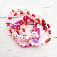 three bracelets with words and hearts on them sitting next to each other in front of a white wooden background