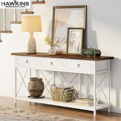 a white console table with two drawers and baskets on the bottom shelf next to a lamp