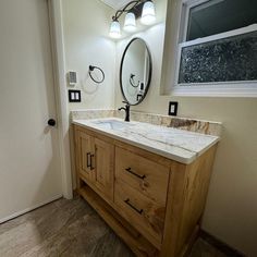 a bathroom with a sink, mirror and light fixture in it's center area