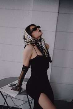 a woman in black dress sitting on top of a table