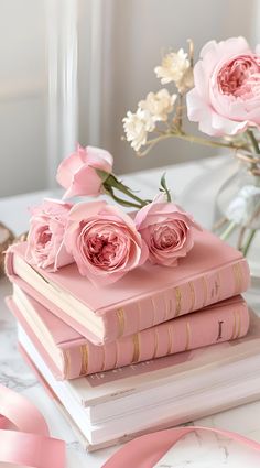 three books with pink flowers on top of them