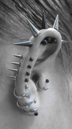 a woman's ear with spikes attached to the back of her ear is shown in black and white