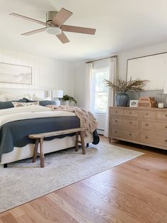 a bedroom with a bed, dresser and ceiling fan in the middle of the room