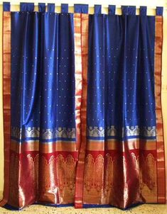 blue and red silk saree with gold border hanging on a wall in front of a window