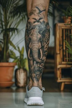 an elephant and birds tattoo on the leg of a person's legs, with plants in the background