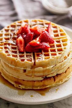 a stack of waffles with syrup and strawberries on top