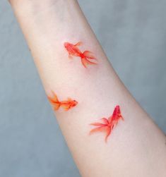 two goldfishs on the arm with red ink all over their body and wrist