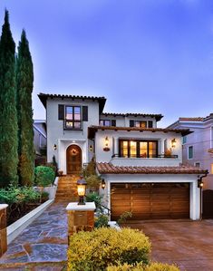 a large house with lots of windows and lights in front of the entrance to it