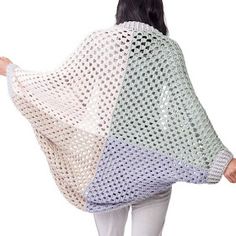 a woman is wearing a crocheted shawl and white pants with her back turned to the camera