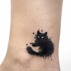 a black cat tattoo on the ankle with ink splatters all over it's body