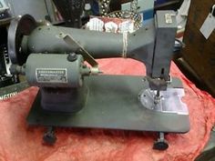 an old sewing machine sitting on top of a red cloth covered tablecloth with other items in the background