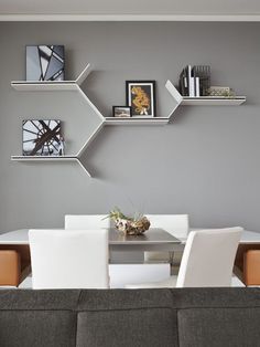 a living room filled with furniture next to a wall mounted book shelf above a dining table