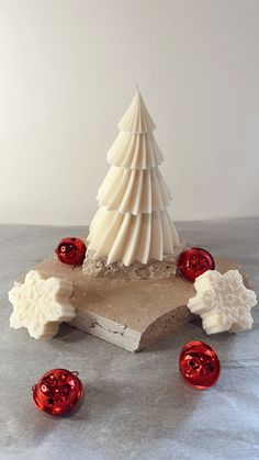 a small white christmas tree sitting on top of a piece of wood next to candy