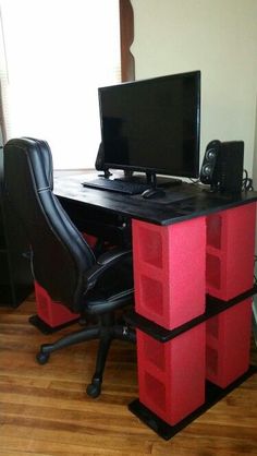 a computer desk with two red boxes on it and a black chair next to it