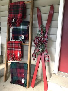 red and green plaid scarfs hanging on the side of a house with a ladder