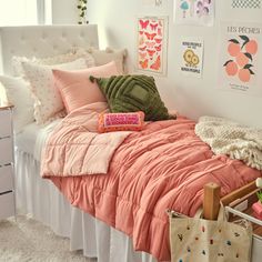 a bed with pink comforter and pillows in a bedroom next to pictures on the wall