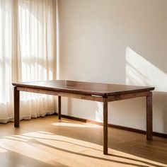 a wooden table sitting on top of a hard wood floor in front of a window