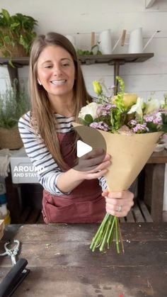 a woman holding a bouquet of flowers in front of her face and smiling at the camera