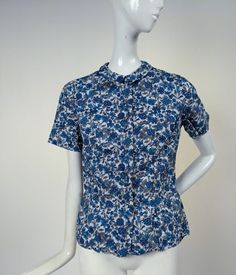 VINTAGE 1960’S BLUE FLORAL PRINT COTTON BLOUSE BY JOHN DOUGLAS DATING TO THE 1960’S FASHIONED OF COTTON WITH A BEAUTIFUL PRINT.  SELF COVERED BUTTONS CLOSE UP THE FRONT WITH A NARROW COLLAR AROUND THE NECKLINE.   LABELED ON THE INTERIOR JOHN DOUGLAS.   CONDITION:  FRESHLY HAND LAUNDERED, NO FLAWS FOUND.   SIZING: MEASUREMENTS IN INCHES: CHEST:  34  WAIST:  27   LENGTH:  20  our business name is ANTIQUE WARDROBE . We can be found online on other platforms as well (Antiquewardrobe_ as well as Anti