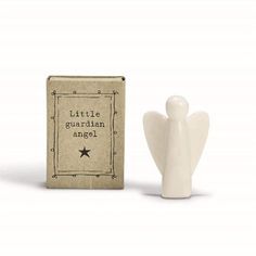 a small white angel figurine next to a cardboard box that says little guardian angel