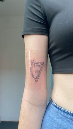 a woman with a tattoo on her arm holding a small harp in the shape of a heart