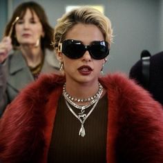 a woman wearing sunglasses and a red fur coat is standing in an elevator with other people behind her