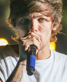 a close up of a person holding a microphone to his mouth and looking at the camera