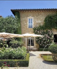 an outdoor area with tables, chairs and umbrellas in front of a stone building