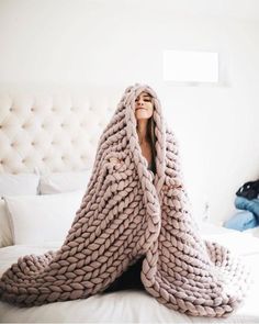 a woman wrapped in a blanket on top of a bed