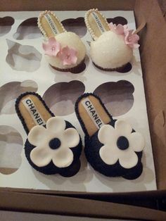 three pairs of black and white shoes with flower decorations on them in a cardboard box