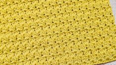 a yellow crocheted dishcloth is laying on a table