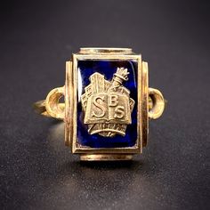 The tradition of class rings originated with the class of 1835 at the United States Military Academy at West Point. From there, the practice of a dated ring signifying ones alma mater became a popular fashion, worn as a symbol of pride and accomplishment. This piece has been converted to a ring from a school pin. The detailed face shows a cityscape in the background with a torch and open book bearing the initials S B S. Riveted to a cobalt blue spinel stone with a closed back, it has a wonderful vintage graphic feel, perfect for bookworms everywhere! Details (approximate) Size: 7.5 Weight: 5.8 grams Materials: Gold, Blue Spinel Metal: 10K yellow gold, 14K yellow gold Marks: Shank: Stamped KC & S; 9, 375, Maker's mark, 14K. Ring back: 10K, M.A.A. Condition: Very good vintage condition This Heirloom 14k Gold Signet Ring For Commemoration, 14k Gold Heirloom Signet Ring For Commemoration, Heirloom Engraved Ring For Commemoration With Hallmarks, Antique 14k Gold Engraved Ring For Commemoration, Classic Engraved Enamel Ring For Formal Occasions, Antique Yellow Gold Rings For Commemoration, Classic Engraved Enamel Ring, Classic Engraved Yellow Gold Enamel Ring, Classic Engraved Enamel Ring For Anniversary