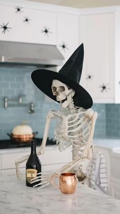 a skeleton in a witches hat sitting at a kitchen counter