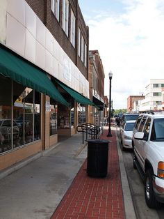 the sidewalk is lined with parked cars in front of shops and businesses on both sides