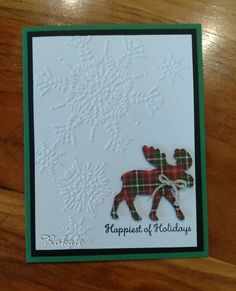 a christmas card with a reindeer and snowflakes in the background on a wooden table