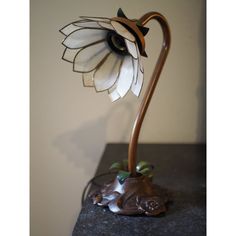 This Vintage Art Nouveau Style Lotus Flower Lamp features delicate mother of pearl petals, forming a graceful lotus flower that softly diffuses light, creating a warm and inviting ambiance.  The lamp’s base is crafted from solid cast iron, ensuring stability and durability, and is finished with a brass-like coating, giving it a luxurious appearance. The stem, which elegantly curves to support the flower, is likely made of brass or a copper alloy with a brown finish that complements the naturalistic design. The green leaves, encircling the base of the flower, are crafted from brass or a similar metal and coated with a vibrant green enamel, adding a pop of color and enhancing the botanical theme of the piece.  Please note that this lamp requires a plug adapter for use in the US, which is inc Lotus Flower Lamp, Naturalistic Design, Art Nouveau Lighting, Witch's Cottage, Pink Table Lamp, Witch Cottage, Botanical Theme, Furniture Lamps, Flower Lamp