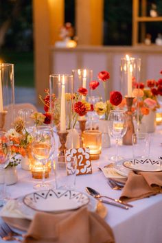 the table is set with candles, plates and napkins for an elegant dinner party