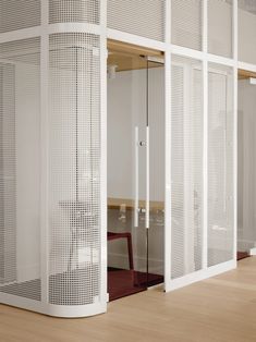 a room divider in the middle of a wooden floor with white mesh coverings