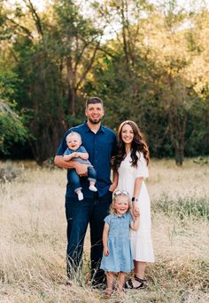 a family posing for a photo in the middle of a field with tall grass and trees