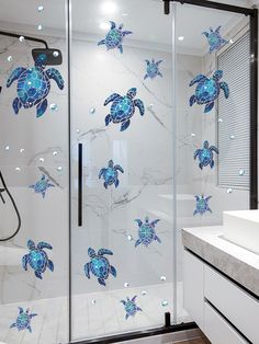 a glass shower door with blue turtles on it