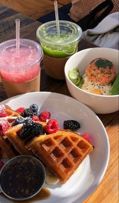 waffles and fruit are served on a white plate with two cups of juice