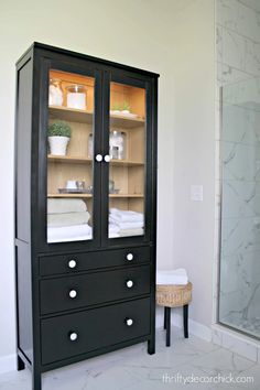 a black cabinet with glass doors in a bathroom