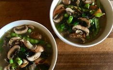 two bowls filled with soup sitting on top of a wooden table