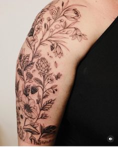 a woman's arm with flowers and leaves on it