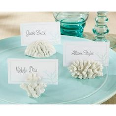 three place cards are placed on a plate with corals and seashells in the background