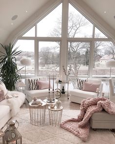 a living room filled with lots of furniture and large windows covered in white blankets on top of