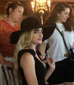 a woman wearing a black hat standing next to other women